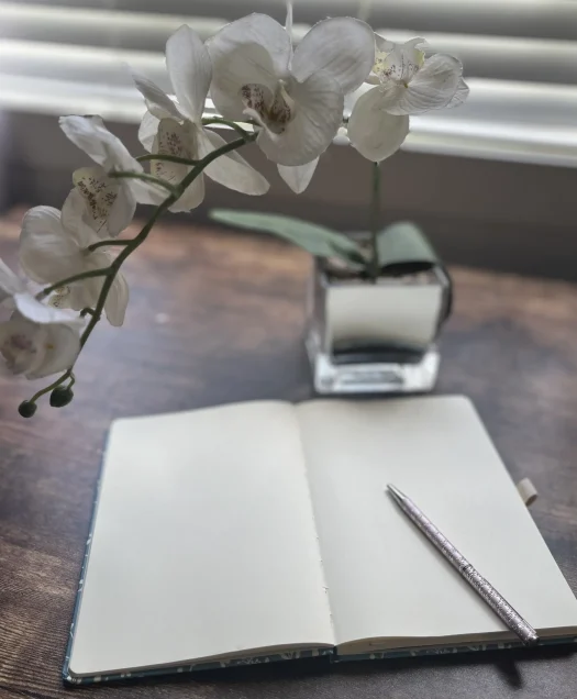 notebook on desk with flower in foreground